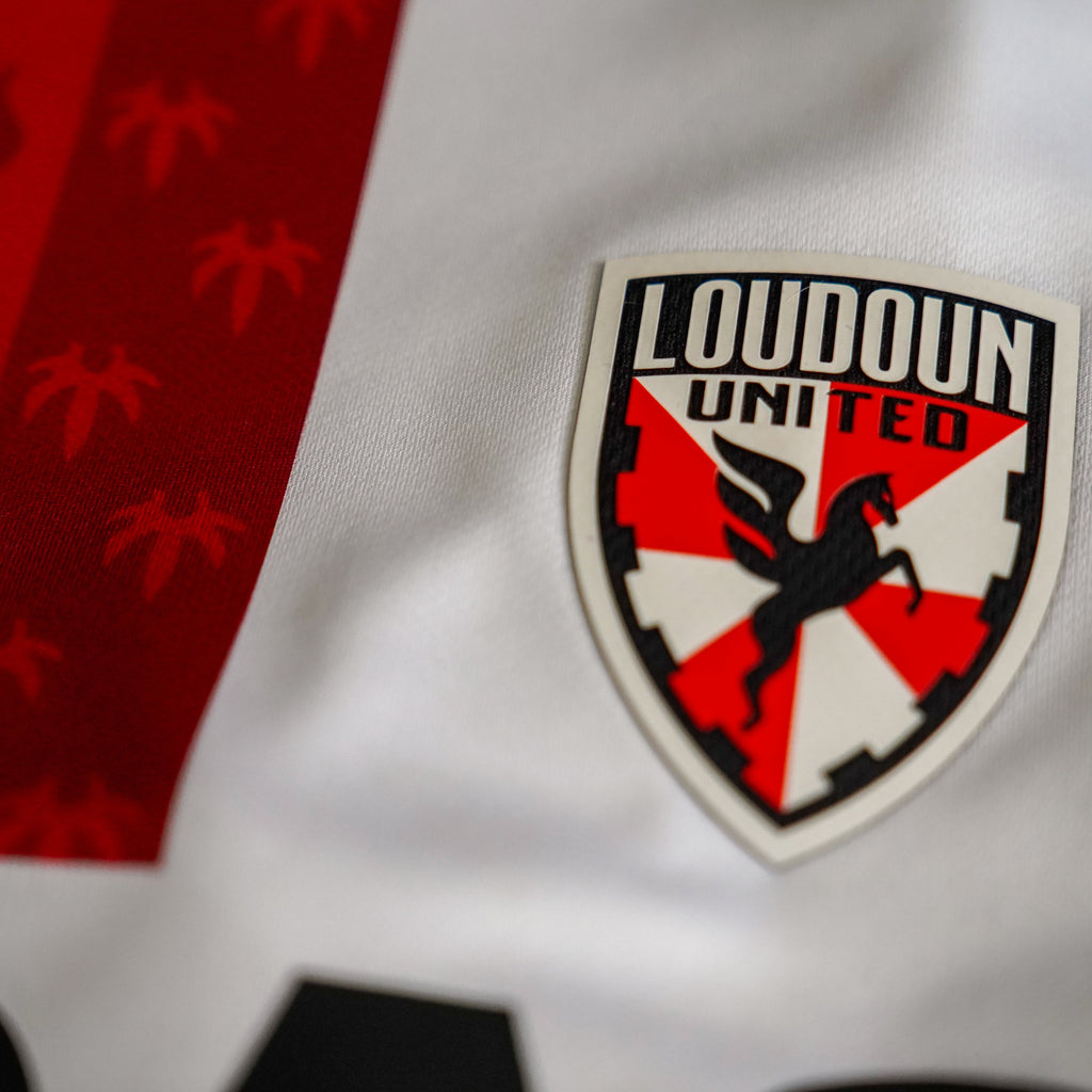Loudoun United logo on a sports jersey with red and black design elements.