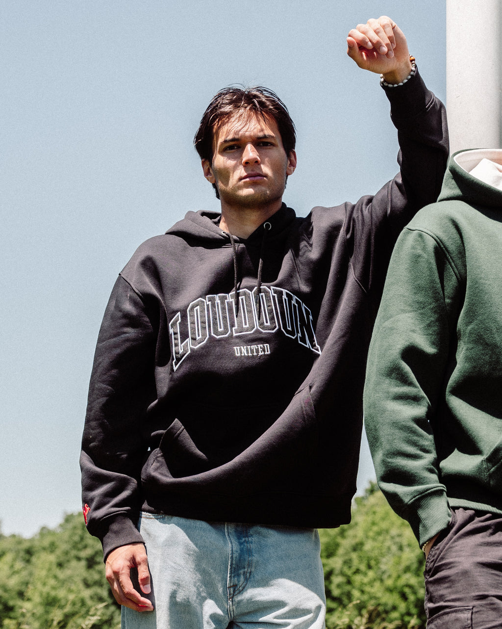 Person wearing a black hoodie with 'Loudoun United' text outdoors.