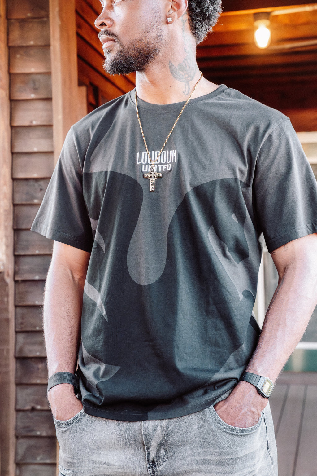 Man wearing a dark gray t-shirt with a logo, standing indoors.
