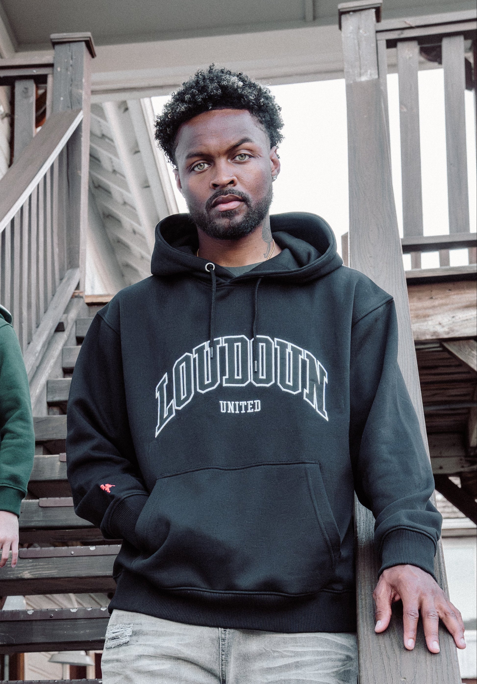 Two people wearing hoodies on a wooden staircase.